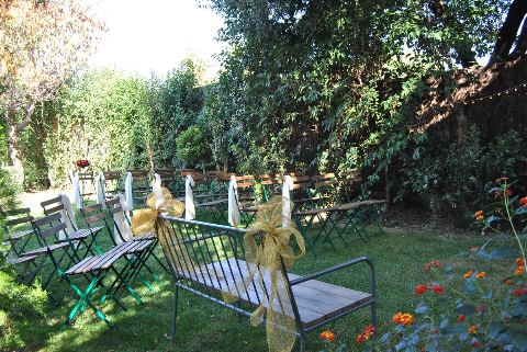 Banc de ferro amb un llaç daurat i fileres de cadires entre flors del jardí