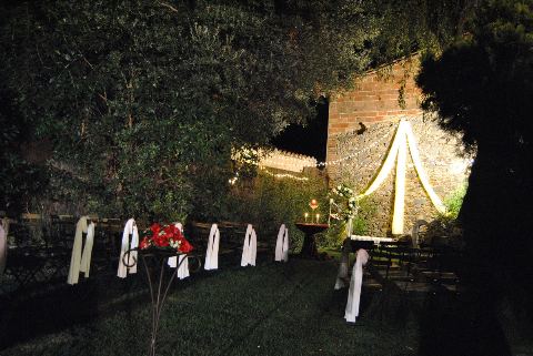 Cadires amb xals i ram de flors vermelles de nit, amb l'arc il·luminat al fons