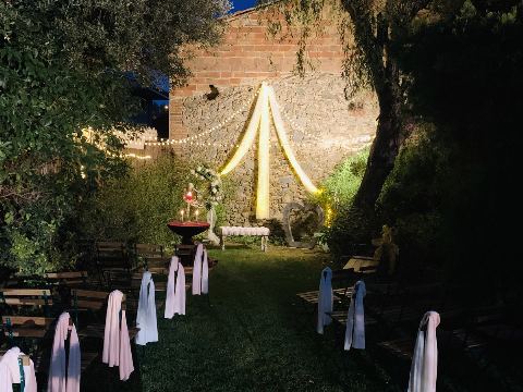 Cadires amb xals de colors al jardí en caure la tarda, amb l'arc il·luminat