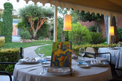 Mesa puesta con un cuadro de colores y el jardín al fondo