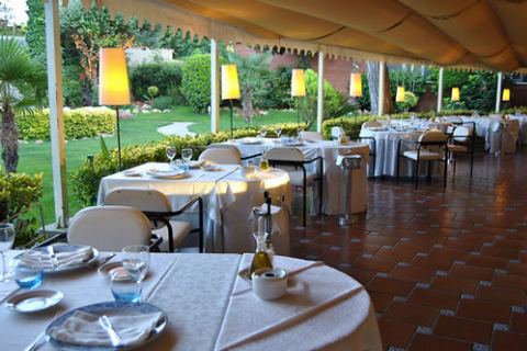 Terraza cubierta al atardecer con lámparas encendidas y mesas puestas
