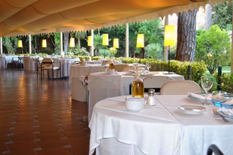 Detalle de una mesa con aceitera, copas y servilletas bajo el toldo