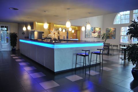 Bar del salón con barra iluminada en azul y taburetes altos