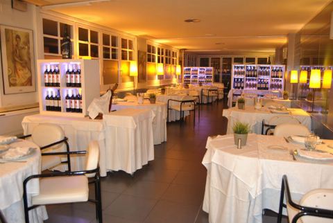 Sala con mesas puestas y vitrinas de vino iluminadas al fondo