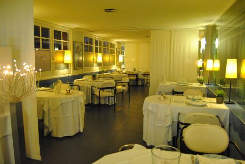 Sala con lámparas de pie y mesas puestas junto a los ventanales