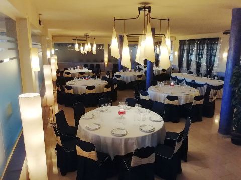 Sala amplia con cortinas oscuras, mesas redondas y una columna azul