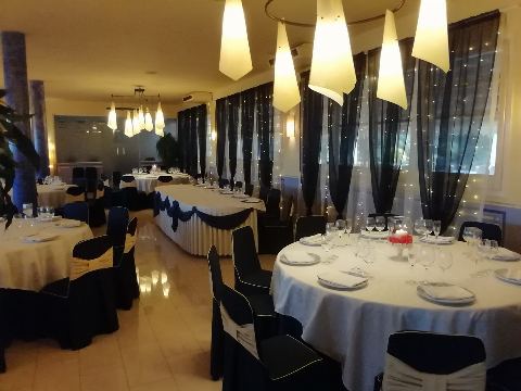 Mesas redondas con fundas de silla azul oscuro y cortinas con lucecitas